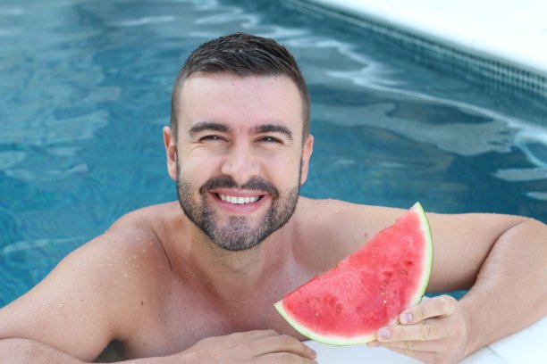 一个男人在游泳池里享受健康的水果图片下载