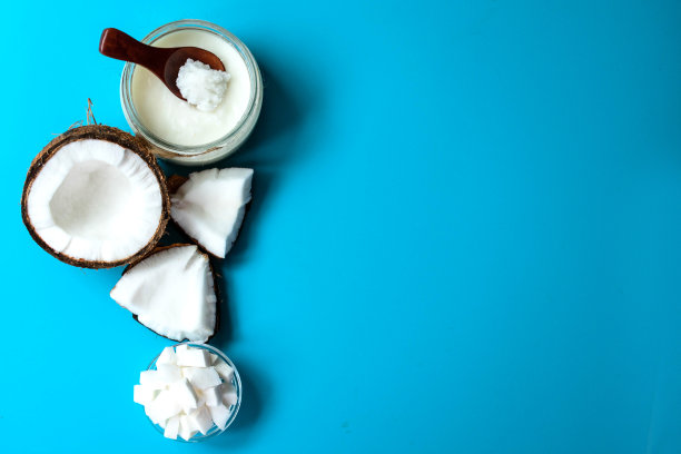 浅蓝色背景的玻璃罐中椰子油。平的。副本的空间。图片下载