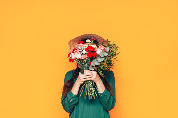 一个女人拿着一大束花，穿着黄色背景的绿色裙子图片下载