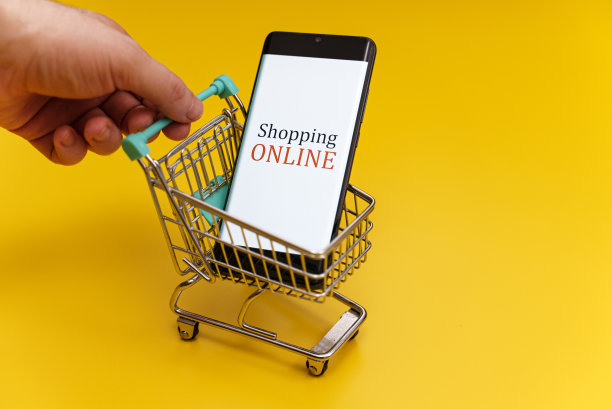 黄色背景的智能手机购物车。网上购物的概念。图片下载