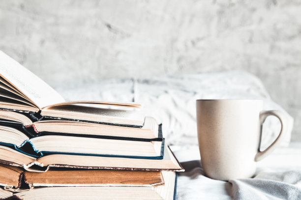 一堆打开的书和一杯咖啡躺在床上图片下载