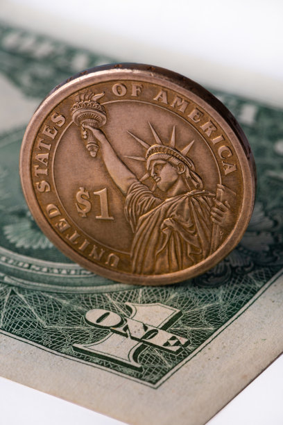 面值为一美元的硬币，以一美元纸币的碎片为背景图片下载