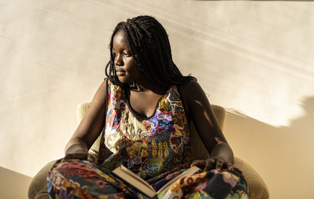 一个非洲妇女坐在家里，手里拿着一本书图片下载