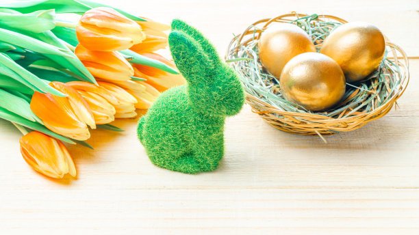 复活节彩蛋篮子里。金蛋篮子与春天的郁金香，白色羽毛的木制背景在快乐复活节装饰。传统装饰在阳光下。图片下载