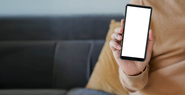 近距离的男人手持智能手机与空白空白屏幕(添加内容)在客厅的商业和技术生活理念图片下载
