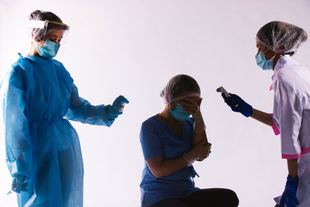 黑暗的照片。卫生工作者健康状况不佳。抱着头的女医生。护士用非接触式温度计测量温度并准备疫苗。图片下载