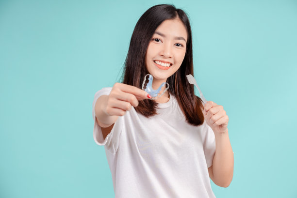 美丽的微笑年轻的亚洲妇女与固定架和牙刷白牙齿增加信心，健康的蓝色背景孤立，快乐的青少年面部表情。图片下载