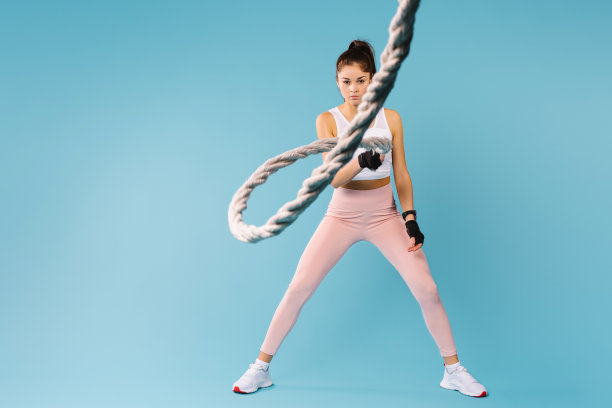 一个调皮的黑发女孩，蓝色背景上系着一根绳子，看着镜头。空白的侧广告空间。图片下载