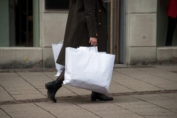 购物后，一个女人拿着许多纸袋走在街上图片下载