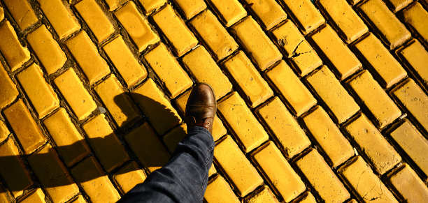 男人的脚穿着棕色的靴子和鞋子停留在活泼的黄色鹅卵石上图片下载