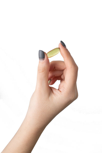 女孩手里拿着一把黄色的药片，白色的背景。鱼油，欧米加3图片下载