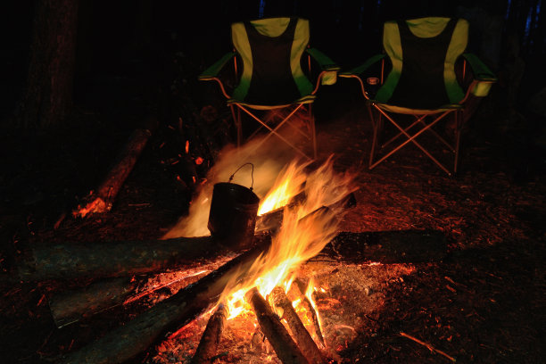 晚上篝火在河边的森林空地上，火星和壁炉。图片下载