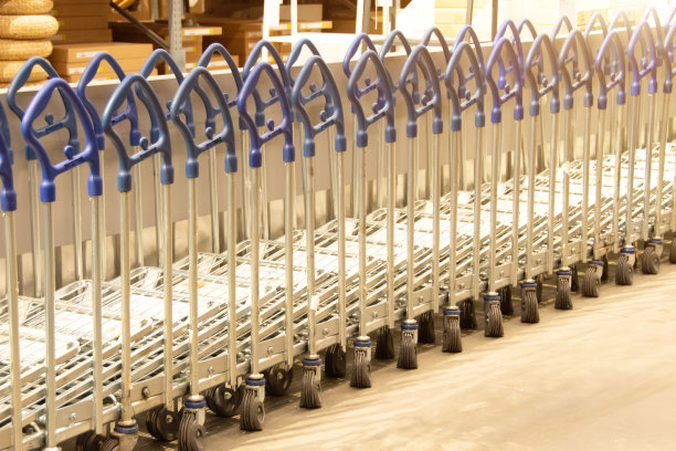 零售商店的仓库存储。在超市仓库的零售商店的超大货架区之间排各种购物车。图片下载