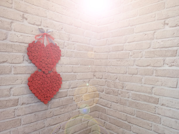 房间角落的砖墙上挂着红心。爱的象征图片下载