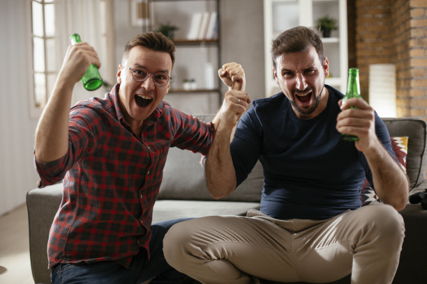 男人喝啤酒，看电视上的体育比赛。图片下载
