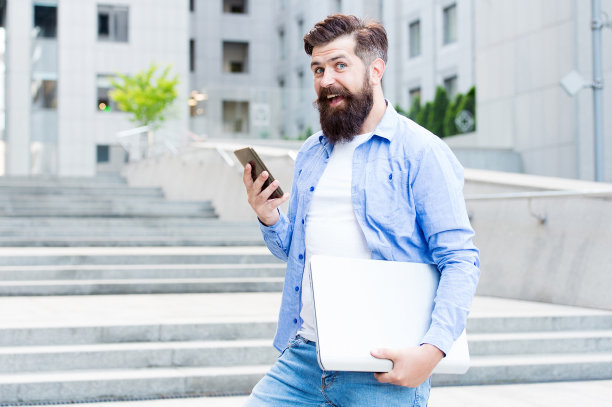 在社交距离时代工作。一个人带着笔记本走在空荡荡的街上。商务中心重新开放。现代生活。时髦的现代工人拿着笔记本。要去工作的人，城市背景。现代科技图片下载