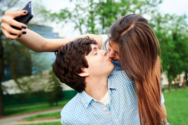 这对年轻幸福的情侣在城市的夏日里亲吻拥抱，这张照片被你的智能手机拍了下来图片下载