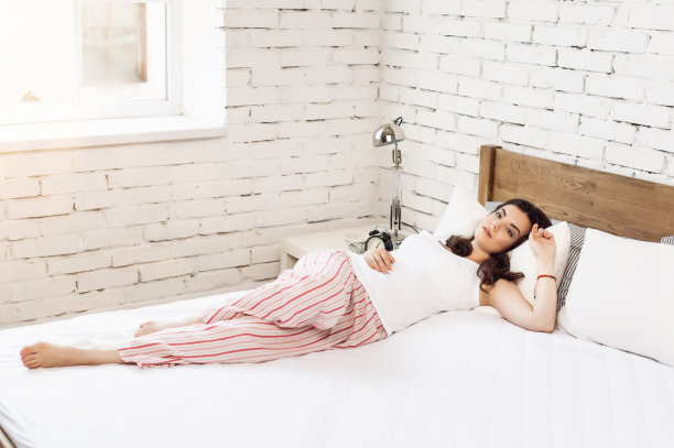 女孩躺在木床上的白色枕头和床垫上。舒适睡眠的概念。骨科床垫和枕头图片下载