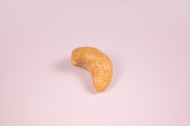 一个去皮的腰果在白色的表面上图片下载