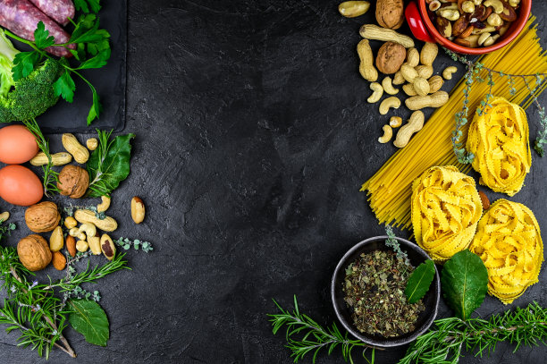 有烹饪背景的香料，香草，蔬菜和芳香香草。，香肠，鸡蛋，意大利面，坚果，干面条在黑色的石头背景。顶部视图与复制空间。烹饪健康的地中海饮食图片下载
