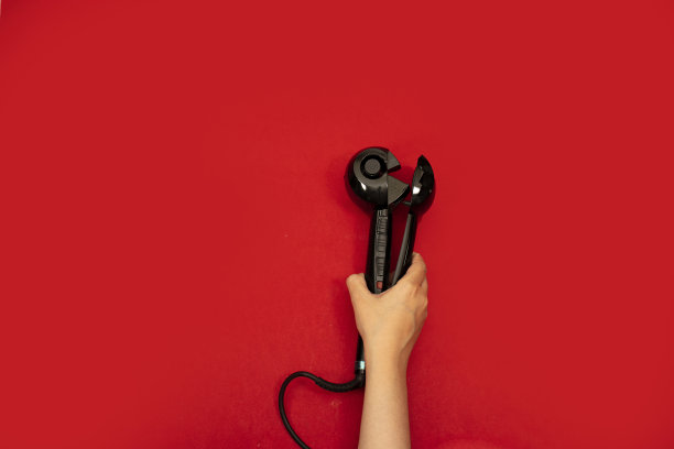 持有自动卷曲头发技术孤立在红色背景图片下载