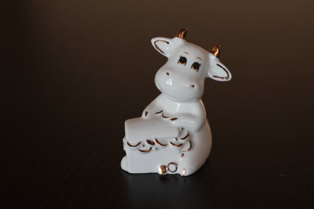 公牛小雕像象征着农历2021年。有角的白奶牛抱着装满财富和健康隔离的盒子图片下载