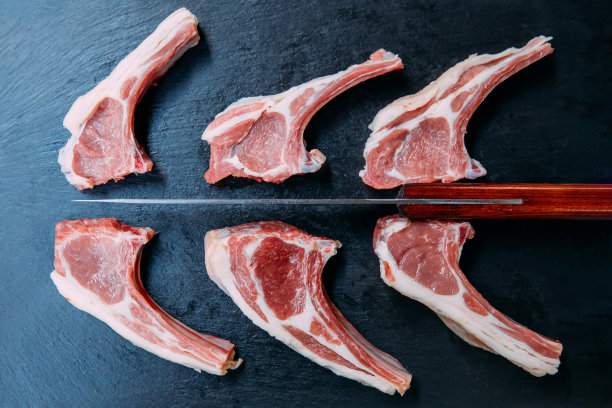 在黑色的背景上，生的和新鲜的羊排肉。素材图片