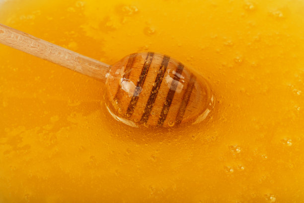 近距离的木勺在蜂蜜碗图片下载