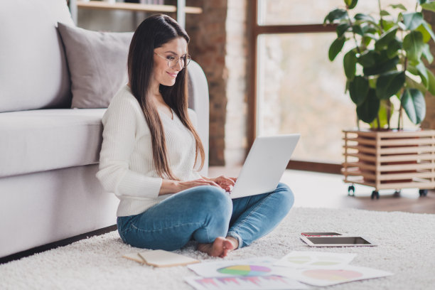 迷人的小姐照片坐在地板赤脚拿上网本戴眼镜白色毛衣在客厅家里室内图片下载