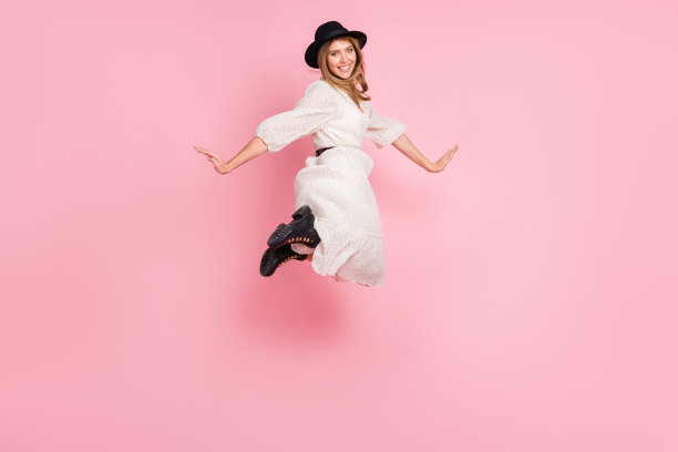 全长照片的滑稽女士跳露齿微笑戴复古头饰点连衣裙靴子孤立的粉红色背景图片下载