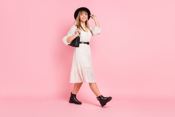 全长照片的女孩走，拿着钱包，穿复古头饰点连衣裙靴子孤立的粉红色背景图片下载