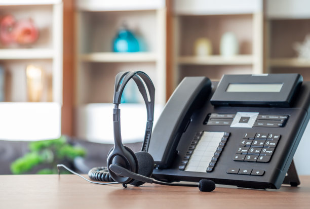 近距离软聚焦耳机与电话设备在办公桌客户服务支持。图片下载