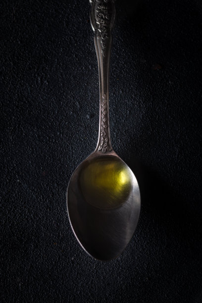 黑色背景的金属勺，配上初榨橄榄油。图片下载