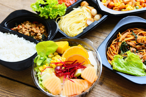 意大利面、通心粉、奶酪、香肠、米饭和水果放在食品盒上，食品递送在家里的木桌上打包带走。图片下载