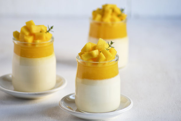 白色背景上点缀着新鲜芒果和芒果冻的意式奶冻。图片下载