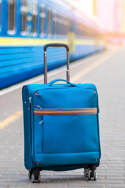 手提行李放在火车车厢附近的站台上。蓝色旅行休闲手提箱图片下载