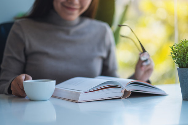 一个美丽的年轻亚洲女人拿着眼镜读书图片下载