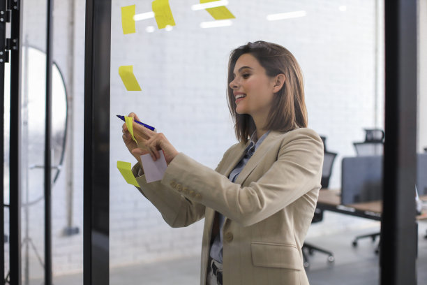照片透过玻璃有吸引力的商业女人张贴在玻璃上的办公室和书写。图片下载