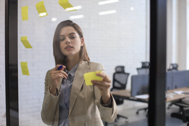 照片透过玻璃有吸引力的商业女人张贴在玻璃上的办公室和书写。图片下载