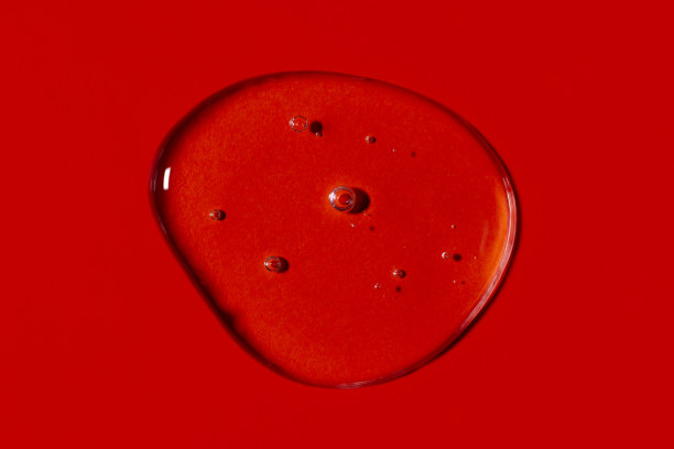 透明的液体凝胶滴或涂片孤立在鲜艳的红色背景上。前视图。病毒防护或化妆品概念。血清纹理。图片下载