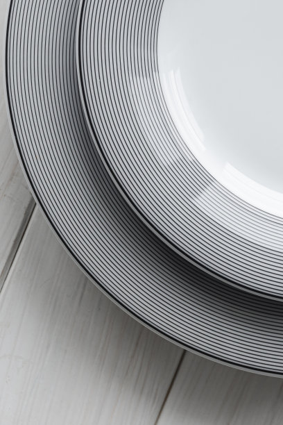 白色桌子上放着白色的灰色花纹的古典圆形瓷盘图片下载