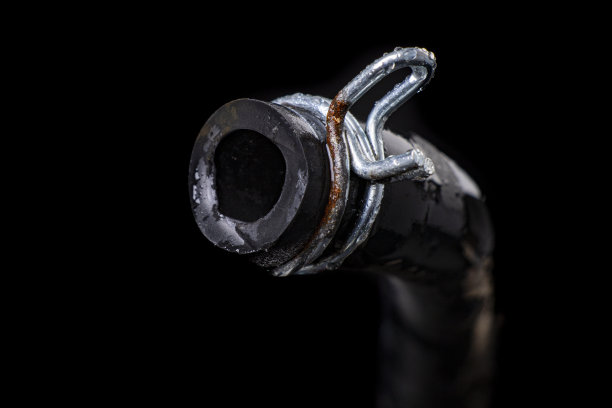 带金属夹的黑色湿软管。修理水和污水系统的水管工的配件和备件。黑色背景。图片下载