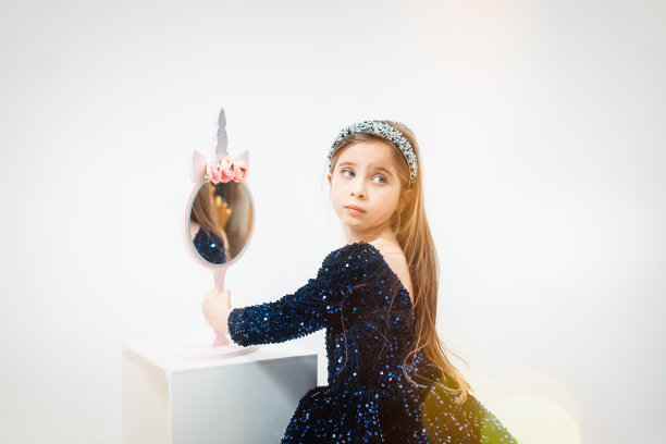 可爱的小女孩用浅蓝色的卷发器在她美丽的脸上化妆图片下载