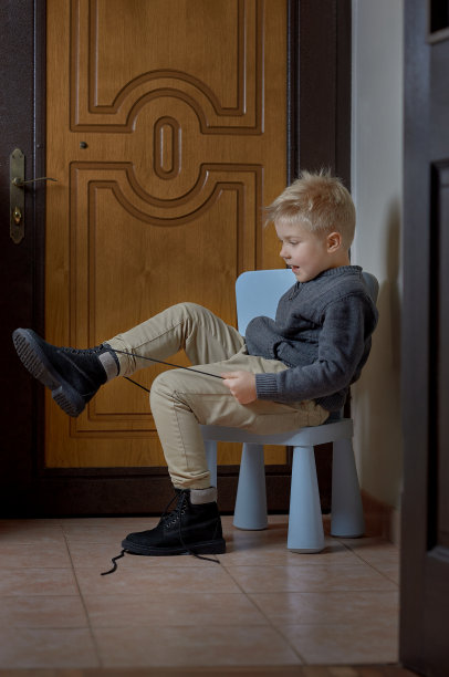 孩子在离家前系鞋带，孩子在看他的靴子图片下载