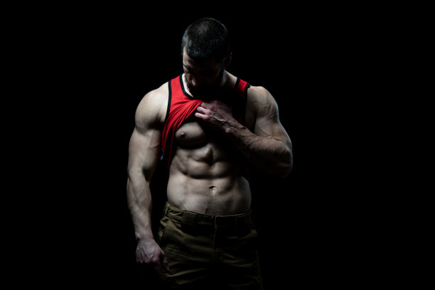 男人站立和弯曲肌肉在黑色的背景图片下载