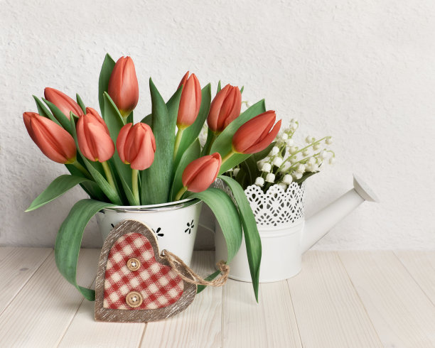 庆祝复活节或春天的生日。简单的贺卡设计。一束郁金香和装饰心由木材和纺织品制成。自然的白色背景，木桌靠墙图片下载