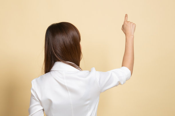 亚洲女人用手指触摸屏幕的背部。图片下载