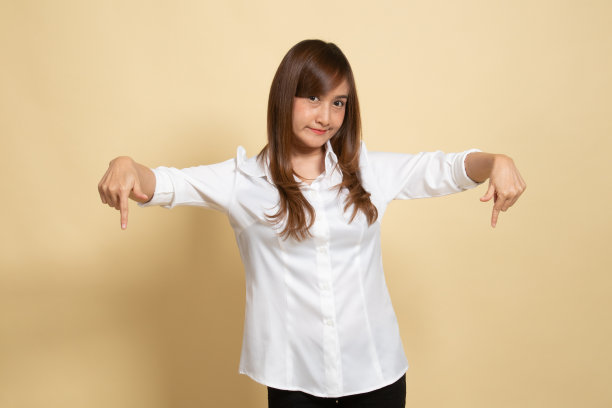 美丽的年轻亚洲女人指向空白的空间。图片下载