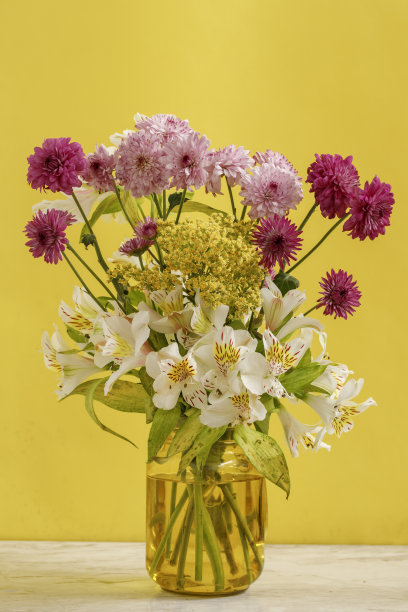 黄色背景的大理石桌子上摆放着极简主义的插花图片下载