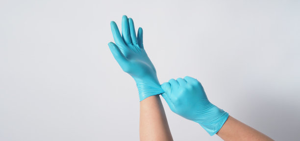 手是拉蓝色外科手套在白色的背景。图片下载